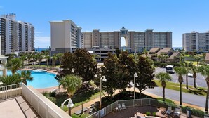 A hotel with a swimming pool, palm trees, and a view of the ocean. - Ariel Dunes II 402 (Miramar Beach)