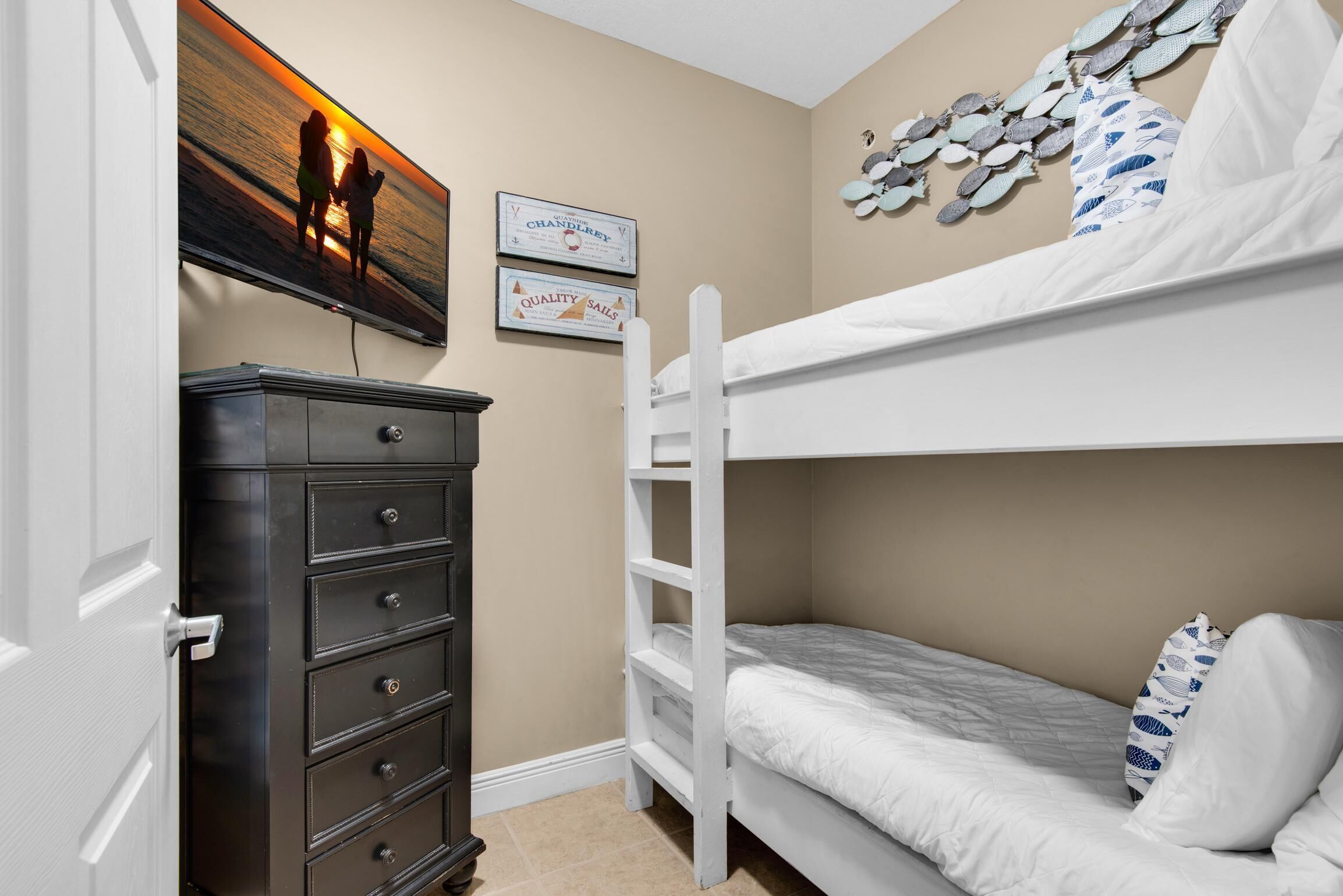 A bedroom with bunk beds, a dresser, and wall decorations including certificates and a fish pattern.