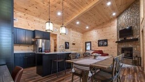 L’intérieur d’une cabane en rondins comprend une cuisine, un coin repas et une cheminée.