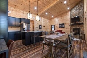 A log cabin interior with a kitchen, dining area, and fireplace.