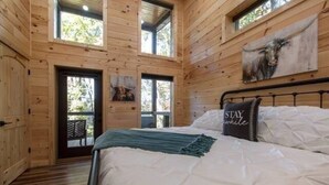 Une chambre dans une cabane en bois, avec un lit, une fenêtre et une porte.