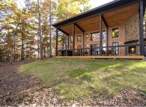 Een chalet met een houten terras, grote ramen en een open haard.