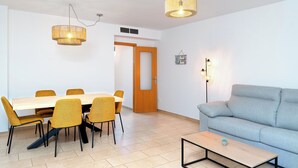 A modern living room with a sofa, a coffee table, and a dining area with a table and chairs. - Edifico Tramontana (Peniscola)