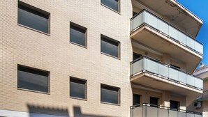 A multi-story building with a modern design, featuring a flat facade, multiple balconies, and a parking area with a white van. - Edifico Tramontana (Peniscola)