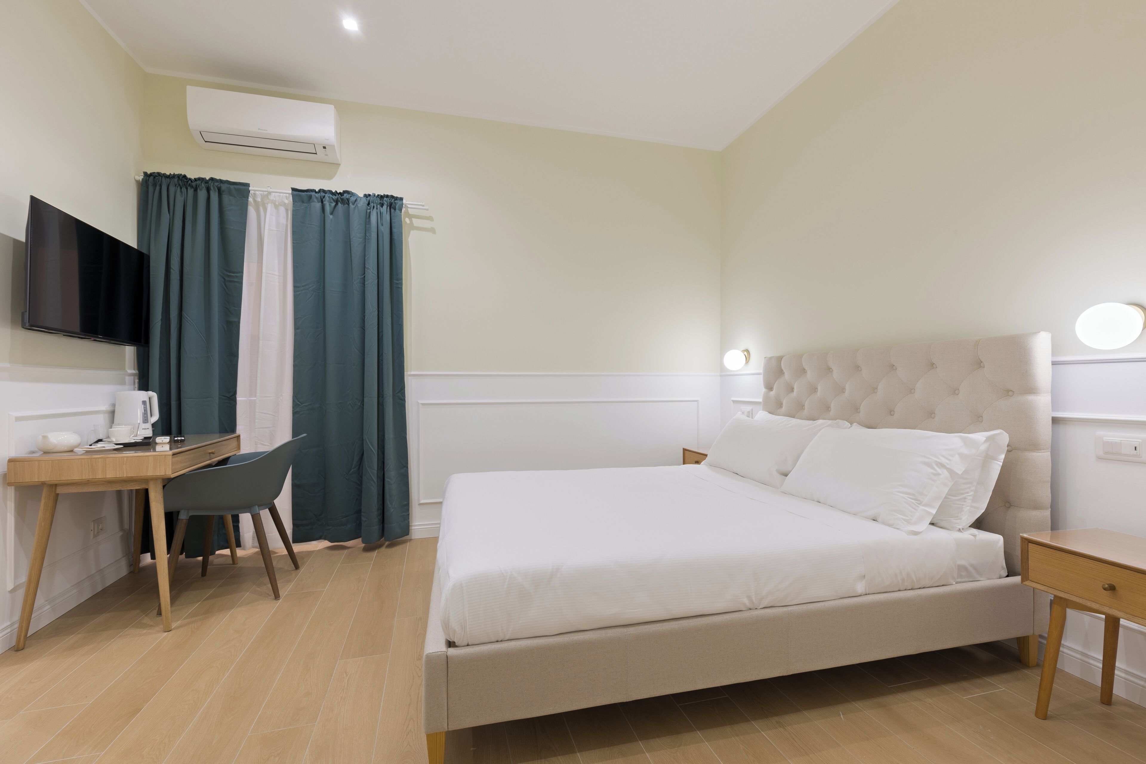 A bedroom with a bed, a desk, a chair, and a television.