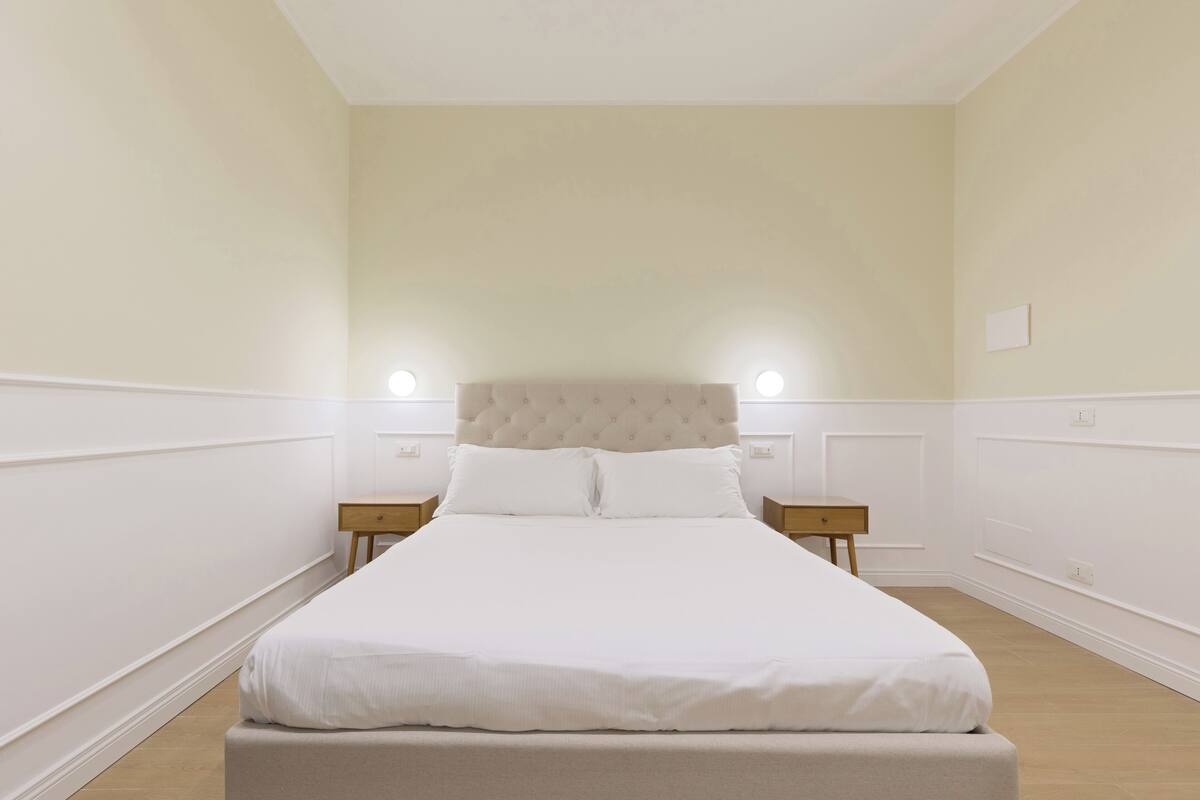 A neatly arranged bedroom with a large bed, two bedside tables, and a headboard.
