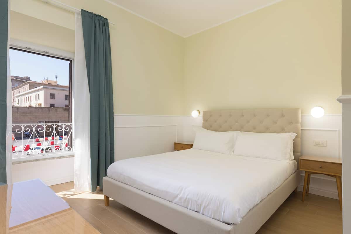 A bedroom with a bed, nightstands, and a window with curtains.