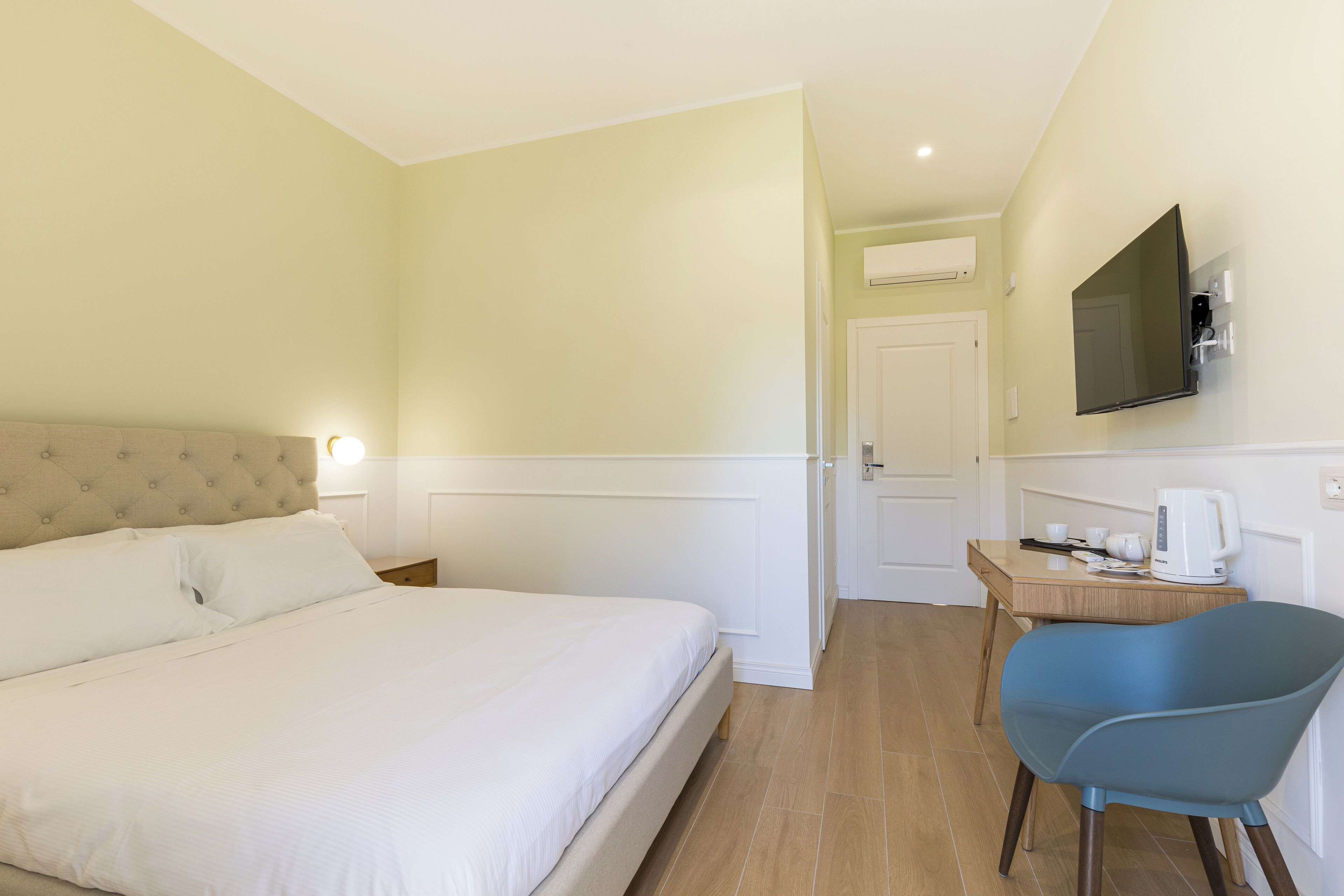 A hotel room with a bed, a desk with a chair, a television, and a coffee maker.