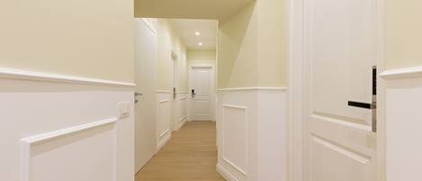 A hallway with white doors and wooden flooring.