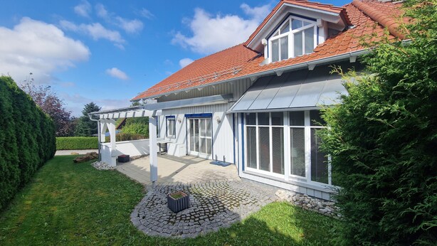 A two-story house with a red-tiled roof, white exterior walls, and a covered patio area. - Living on the golf course in a very quiet location.  (Haarbach)