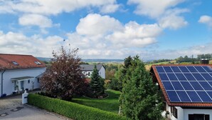A residential area with houses, a solar panel installation, and a clear sky. - Living on the golf course in a very quiet location.  (Haarbach)