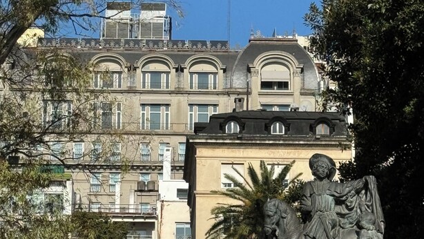 Une statue dans un parc, avec un bâtiment en arrière-plan.