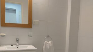 Une salle de bain avec un lavabo blanc, un miroir, un porte-serviettes, un bidet et des toilettes.