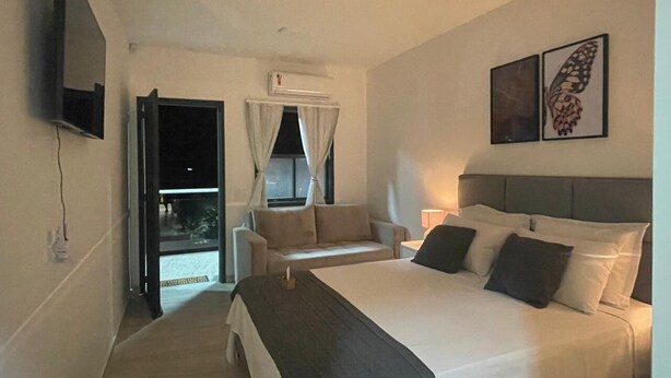 A hotel room with a large bed, a sofa, a TV, and a balcony with curtains. - MORDO DA SERRA (Paty do Alferes)
