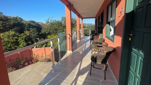 A balcony with a view of a mountainous landscape, a green door, and wicker furniture. - MORDO DA SERRA (Paty do Alferes)