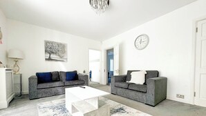 A modern living room with two grey sofas, a white coffee table, and a blue and white patterned rug. - Large 8 Bedroom House in Edgbaston (Birmingham)