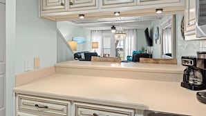 Una cocina con una isla grande, muebles blancos y una lámpara colgante.