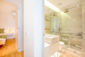 A modern bathroom with a glass-enclosed shower, a marble sink, and a toilet.