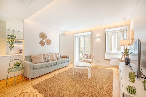 A modern living room with a sofa, a coffee table, a chair, and a TV stand with decorative items.