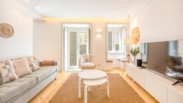 Una sala de estar moderna con un sofá, una mesa de comedor, una silla, un televisor y una lámpara.