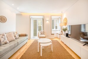 Un salon moderne comprenant un canapé, une table à manger, une chaise, un téléviseur et une lampe.