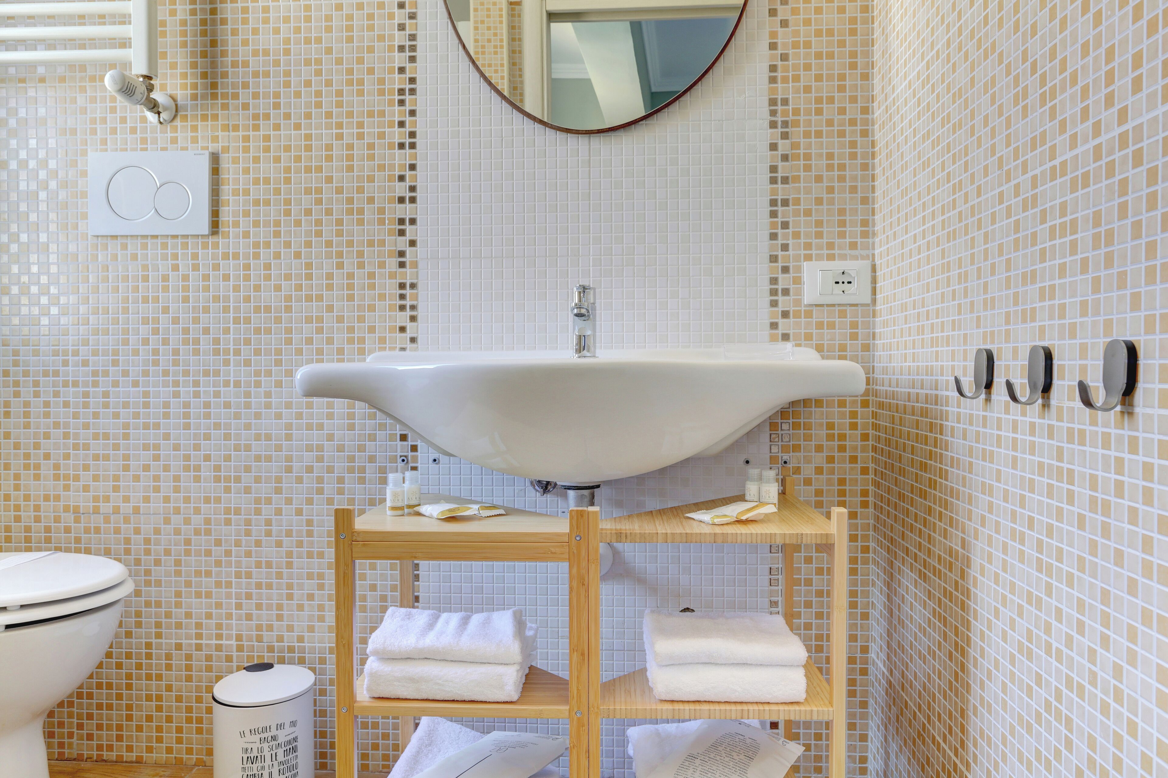 A bathroom with a white sink, a mirror, and a tiled wall.