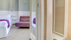 A hotel room with a bed, a pink chair, and a shower area. - Furio Camillo Studio - Metro A - Netflix (Rome)