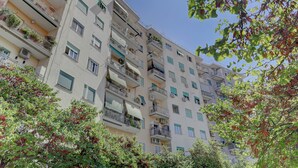 A multi-story residential building with balconies, air conditioning units, and a clear sky. - Furio Camillo Studio - Metro A - Netflix (Rome)