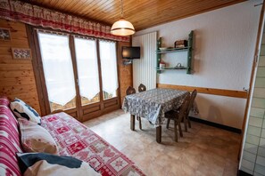 A cozy room with a wooden ceiling, a dining table with chairs, a sofa, and a television on the wall. - 200m from ski slopes, 1st floor, balcony, parking, tv, ski locker, 29m², Les Gets (Les Gets)