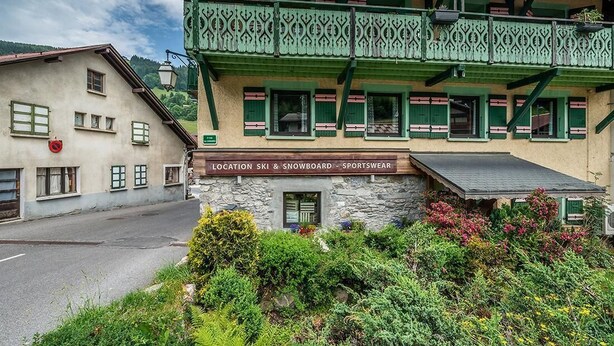 Een gebouw met een bord waarop staat dat het een verkooppunt is voor ski- en snowboardkleding.