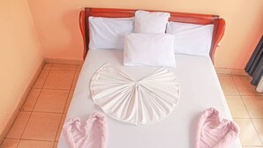 A neatly made bed with white linens, a wooden headboard, and two pillows. - Hirwa Avenir (Kigali)