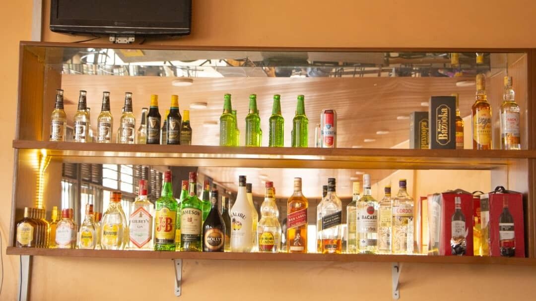 Een bar met meerdere planken vol verschillende drankflessen.