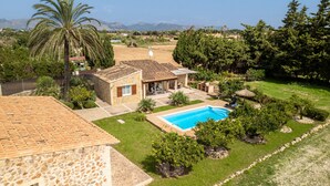 Una casa con piscina, circondata da un giardino curato e vista sulle montagne.