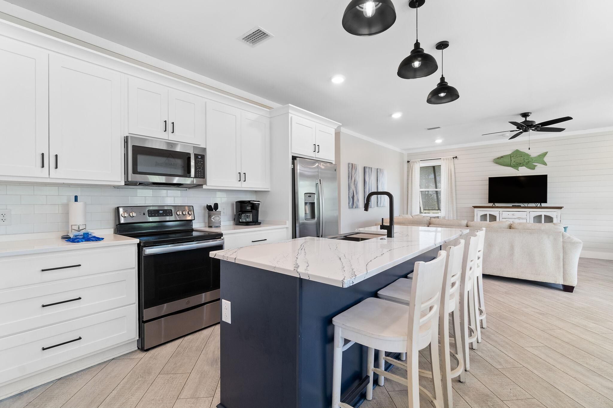 A modern kitchen with white cabinets, stainless steel appliances, and a marble island.