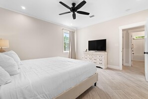 A bedroom with a bed, a TV, a ceiling fan, and a window. - Beach Please (Gulf Shores)