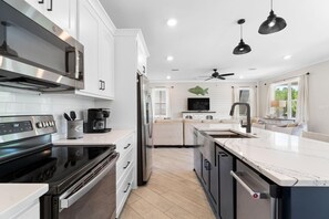 A modern kitchen with stainless steel appliances, a central island, and pendant lighting. - Beach Please (Gulf Shores)