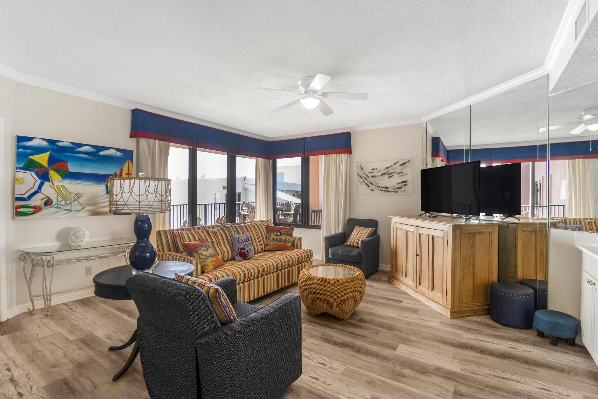 A modern living room with a sofa, armchairs, a television, and a large window with a view.