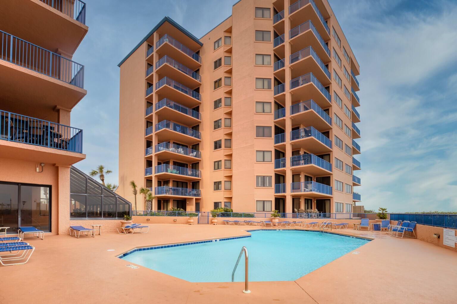 A multi-story hotel with a swimming pool, outdoor seating, and balconies.