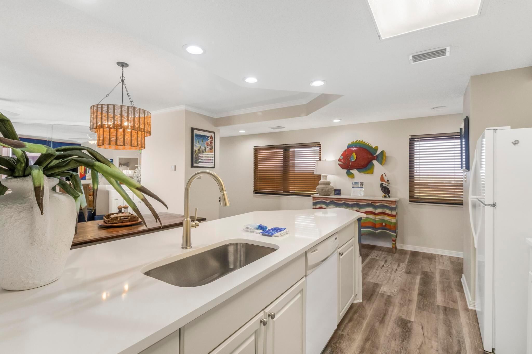 A modern kitchen with a white countertop, stainless steel sink, and a hanging pendant light.