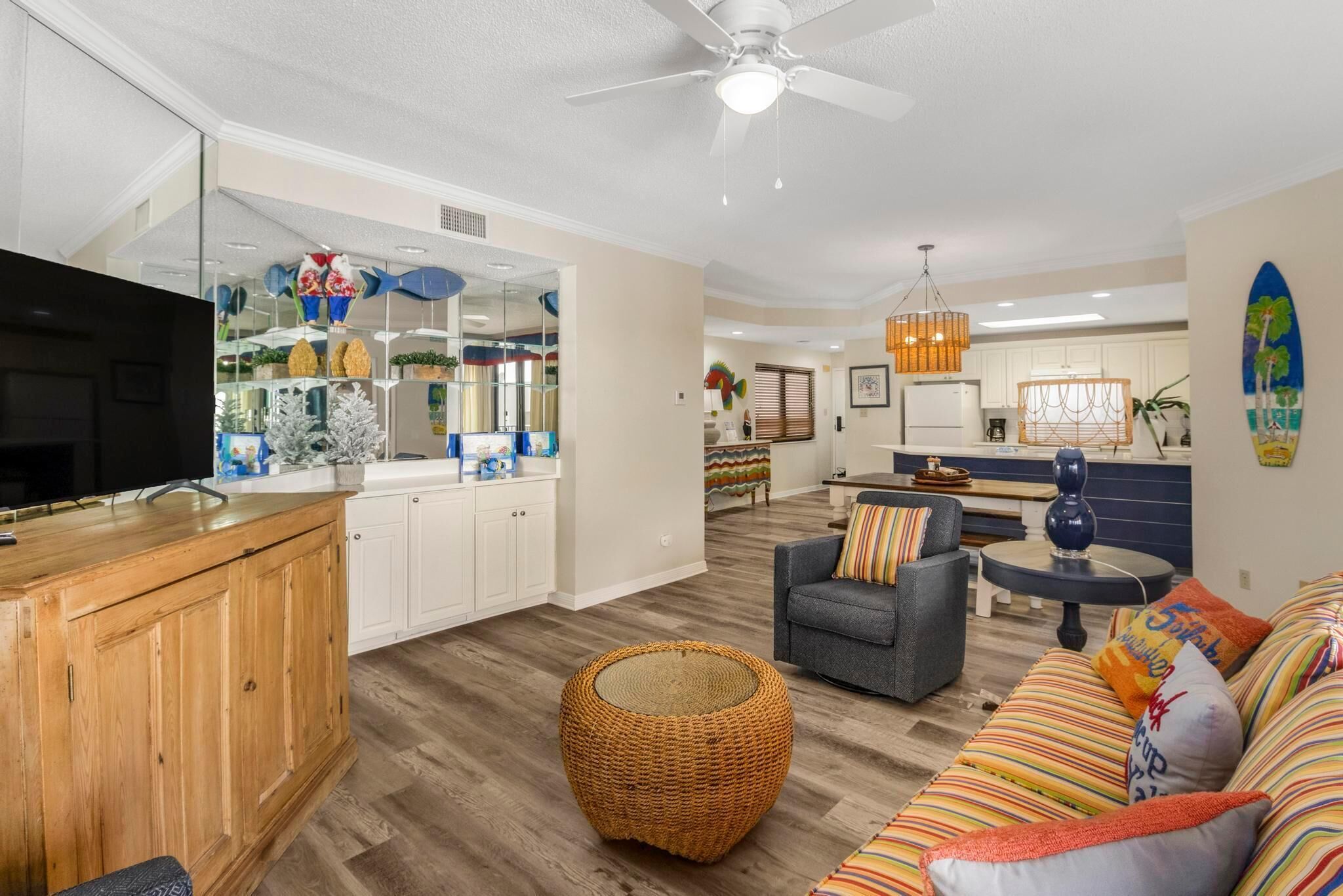A modern living room with a television, a sofa, a coffee table, and a dining area with a kitchen in the background.