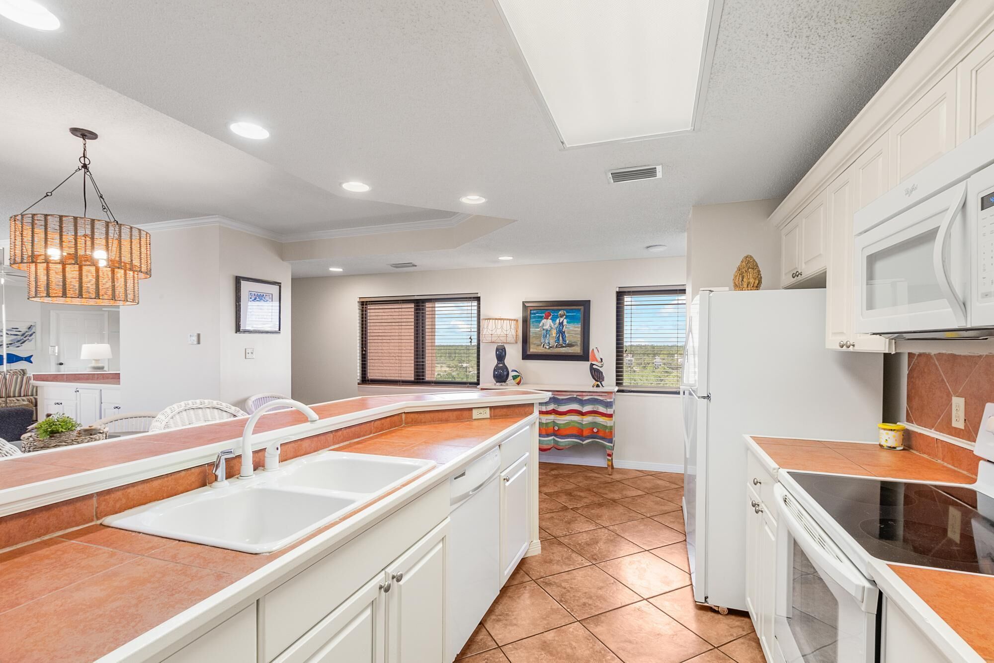 A kitchen with white cabinets, a sink, a stove, and a window with blinds.