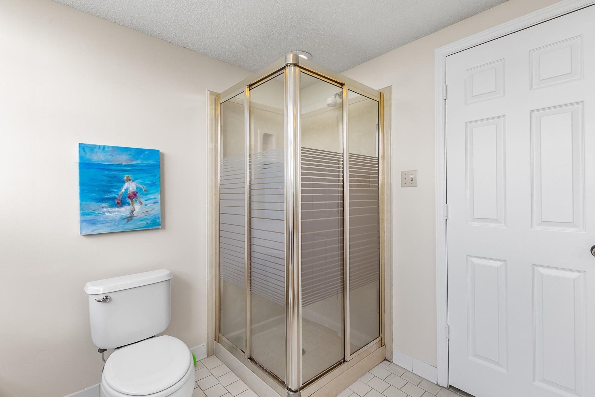 A bathroom with a toilet, a glass shower enclosure, and a door.