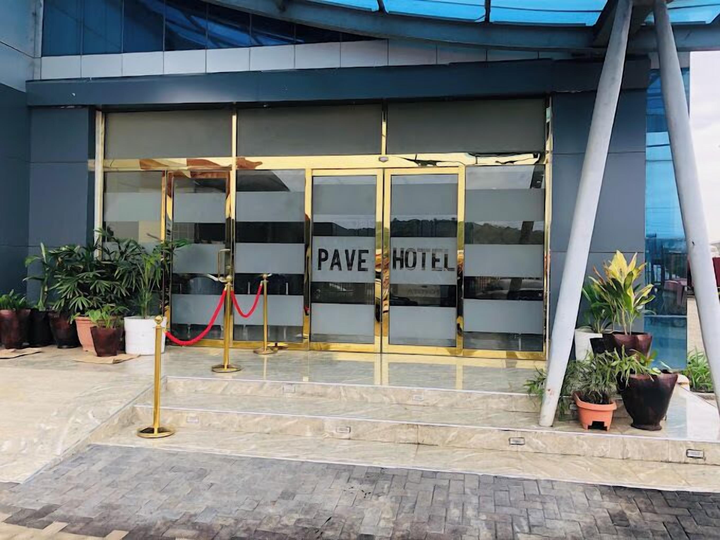 La entrada del Hotel Pave, con puerta de vidrio y una barrera de cuerda roja.