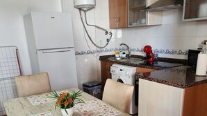 A kitchen with a built-in washing machine, a refrigerator, a sink, and a dining area with a table and chairs.