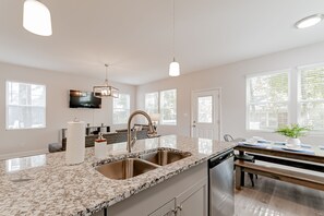 A modern kitchen with granite countertops, stainless steel appliances, and pendant lighting. - Paired On Pope 1 2 (Columbia)