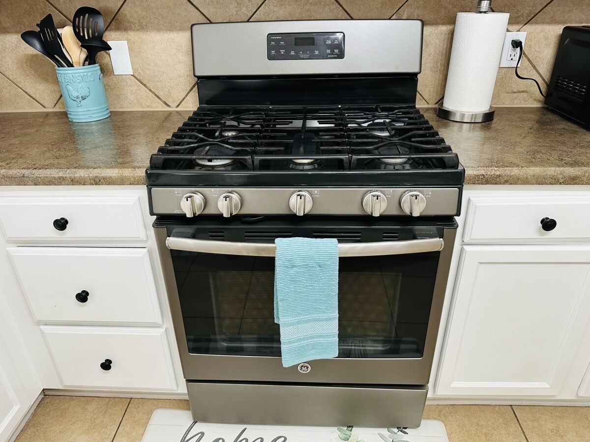 A kitchen with a stainless steel stove, oven, and a blue towel hanging on the oven door.