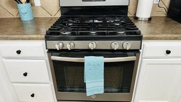 A kitchen with a stainless steel stove, oven, and a blue towel hanging on the oven door.