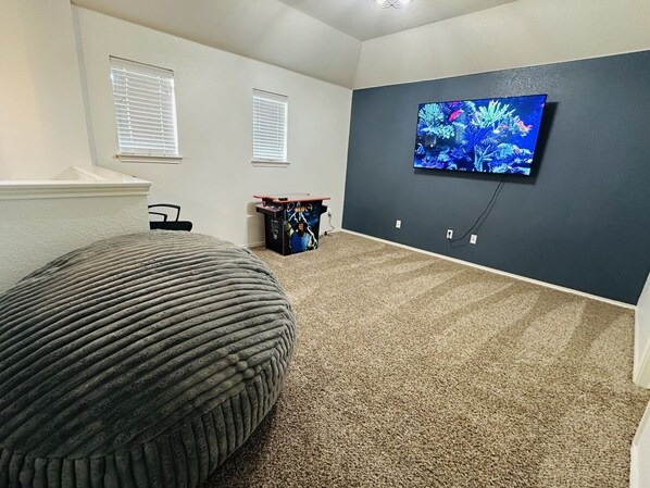 A room with a large bean bag chair, a TV mounted on the wall, and a small entertainment unit.