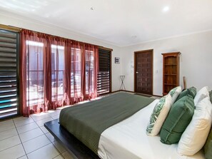 Un dormitorio con una cama grande, cortinas, una lámpara de pie y una puerta.