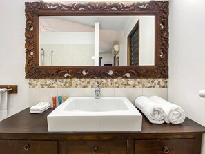 A bathroom with a large mirror, a white sink, and a tiled backsplash.
